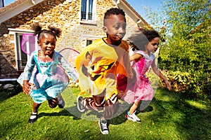 Children group run in Halloween costumes on lawn