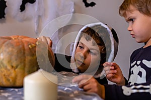 Children in Halloween costumes paint pumpkins. Boy paint pumpkin for holiday. Celebrating at home concept.