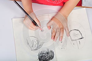 Children hand with pencil draws and sketchs many faces photo