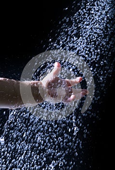 Children hand reach to fresh and pure water drop against black b