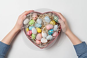 Children hands holding heart shaped box with Easter eggs. White background. Happy easter