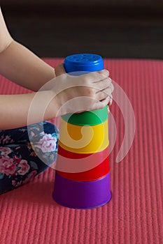 children hands make Pyramid using colorful stacking cups