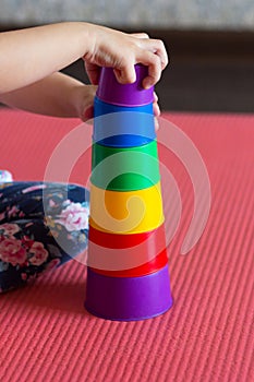 children hands make Pyramid using colorful stacking cups