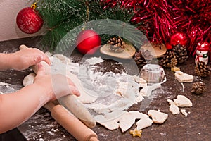 Children hands roll out the dough for Christmas cookies