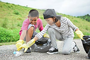 Children hands in yellow gloves picking up empty of bottle plastic into bin bag