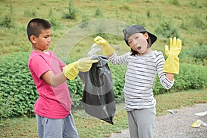 Children hands in yellow gloves picking up empty of bottle plastic into bin bag