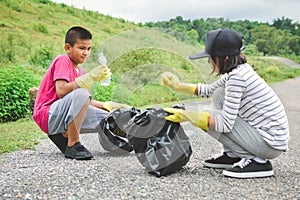 Children hands in yellow gloves picking up empty of bottle plastic into bin bag