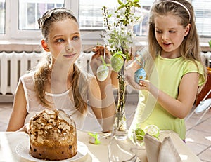 Children hang easter egg on cherry branch.