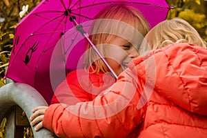 children have fun under an umbrella, in the autumn afternoon