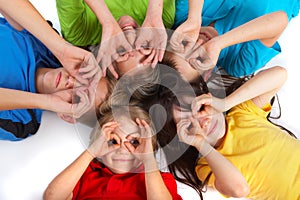Cinque figli di posa in cerchio con le loro teste toccare, giocosamente tenendo le mani in cerchio come gli occhiali da vista sopra occhi.