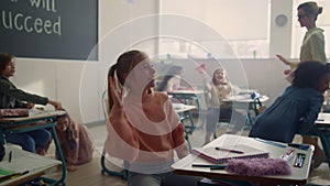 Children having fun in classroom. Mixed race pupils playing with paper planes