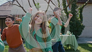 Children having fun dancing at a backyard birthday party on a sunny day