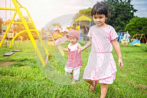 Children having fun little girl holding hand together with love playing outside Asian kids happy in the garden park with