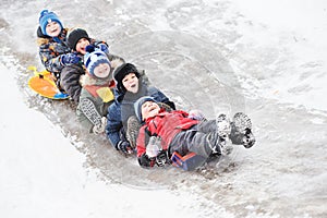 Children having fun riding ice slide in snow winter