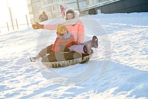 children having fun riding tube ice slide in winter