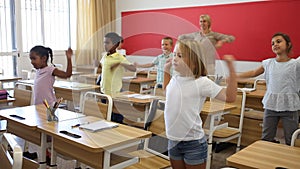Children having physical training with teacher during recess between lessons at classroom