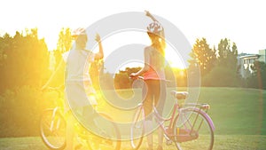 Children in helmet on bicycle rising sun salute in summer park