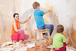 Children help mother remove old wallpapers photo