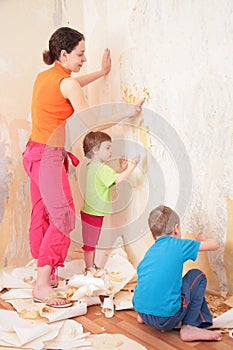 Children help mother remove from wall old wallpap photo