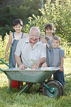 Children is helping her Grandfather in the garden