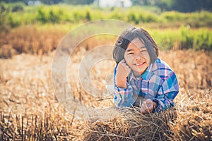 Children helping sweep haystack to pile in rice field of organic farm