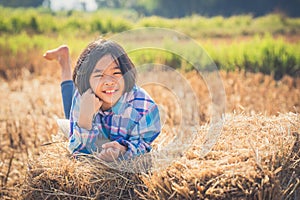 Children helping sweep haystack to pile in rice field of organic farm