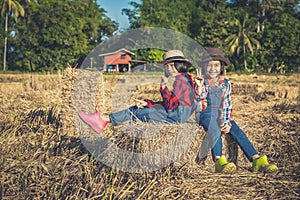 Children helping sweep haystack to pile in rice field of organic farm