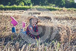 Children helping sweep haystack to pile in rice field of organic farm