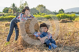 Children helping sweep haystack to pile in rice field of organic farm