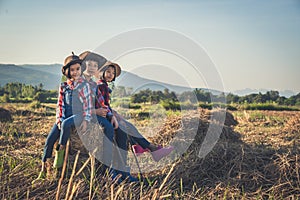 Children helping sweep haystack to pile in rice field of organic farm