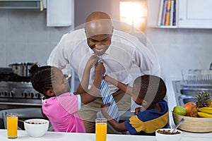 Children helping their father in tying tie