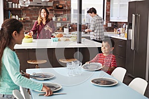 Children Helping To Lay Table Ready For Family Meal