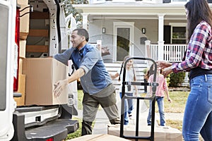 Children Helping Unload Boxes From Van On Family Moving In Day