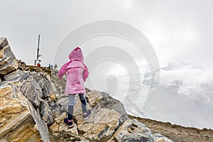 Children hiking in Alps mountains. Kids look at snow covered mountain. Spring family vacation. Little girl on hike trail