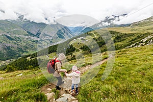 Children hiking in Alps mountains. Kids look at snow covered mountain. Spring family vacation. Little girl on hike trail