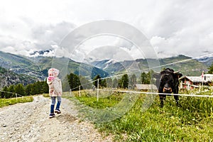 Children hiking in Alps mountains. Kids look at snow covered mountain. Spring family vacation. Little girl on hike trail