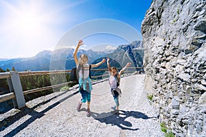 Children hiking on beautiful summer day in alps mountains Austria, resting on rock and admire amazing view to mountain