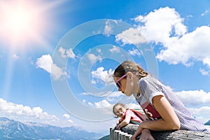 Children hiking on beautiful summer day in alps mountains Austria, resting on rock and admire amazing view to mountain