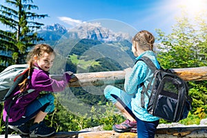 Children hiking on beautiful summer day in alps mountains Austria, resting on rock and admire amazing view to mountain
