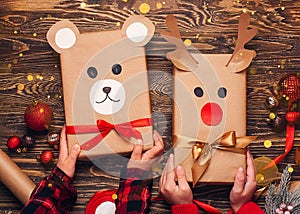 Children hold creatively wrapped Christmas gifts in the shape of a teddy bear and a deer. New Year and Christmas concept. DIY gift