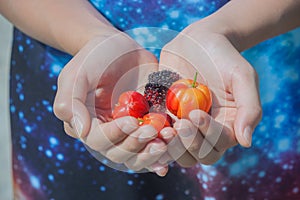 Children holding cherry in hand.
