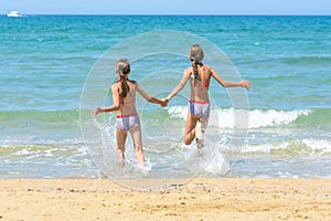 Children holding hands run swimming in the sea