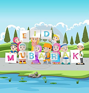 The children are holding the ied mubarak board near the river