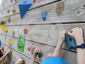 Children holding onto hand grips on a climbing wall