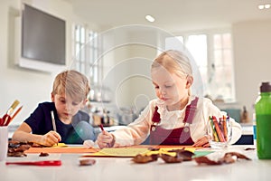 Children At Home Doing Craft And Making Picture Or Card From Leaves In Kitchen