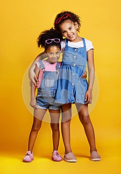 Children, hug and happy portrait of sisters in studio with love, care and support on yellow background. Cute young girl