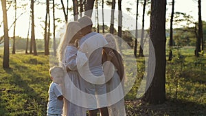 Children hug their parents at forest. Parents and children in white clothes and straw hat are happy