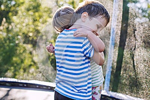 Children hugging in the garden on trampoline. brother with  his little sister