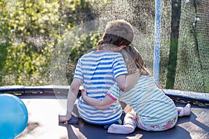 Children hugging in the garden on trampoline. brother with  his little sister