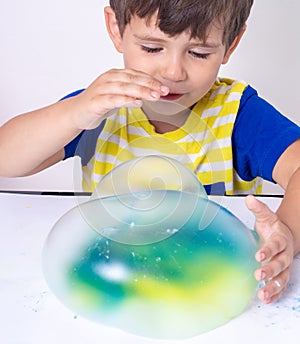 Children inflates a big bubble from a slime. Girl and boy play with slime.
